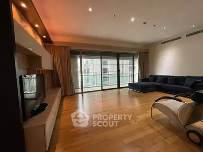 Spacious modern living room with hardwood floors and large windows leading to a balcony.