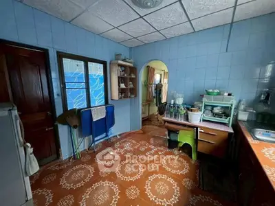 Charming vintage kitchen with tiled walls and patterned floor, featuring open shelving and cozy dining area.