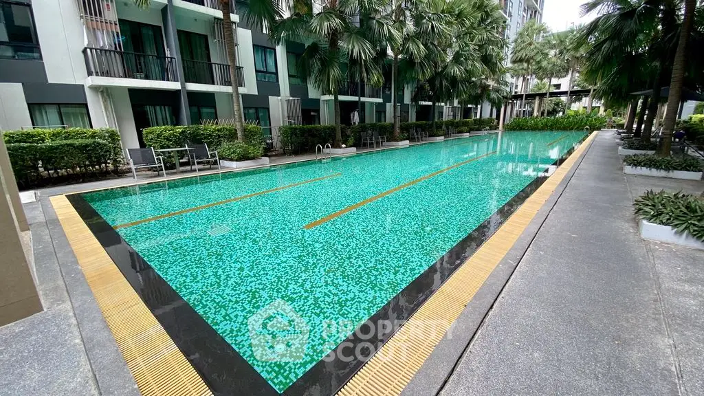 Luxurious condominium pool area with lush greenery and modern design, perfect for relaxation and leisure.