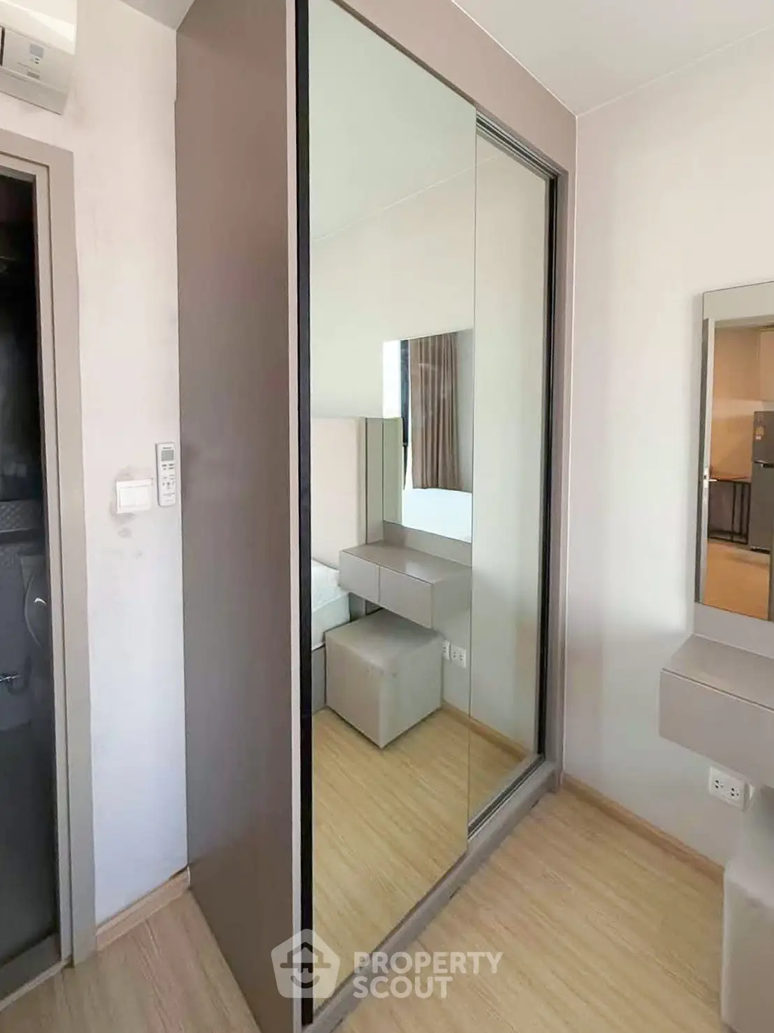 Modern bedroom with mirrored wardrobe and sleek wooden flooring