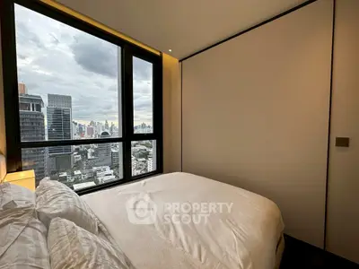 Modern bedroom with stunning city view from large window, featuring cozy bedding and minimalist design.