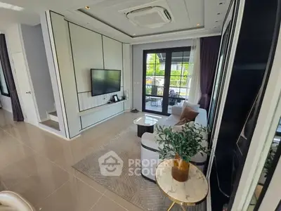 Modern living room with sleek design and large windows opening to a balcony, featuring stylish furniture and decor.