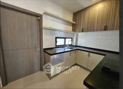 Modern kitchen with sleek cabinetry and black countertops, featuring a minimalist design and ample storage space.