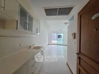 Spacious modern kitchen with sleek cabinetry and open layout leading to bright living area.