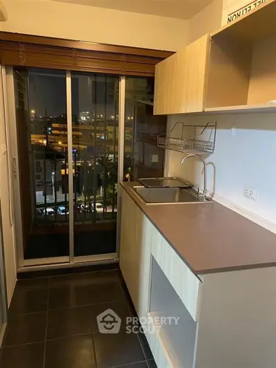Compact kitchen with sliding glass doors and city view, featuring modern cabinetry and sleek countertops.