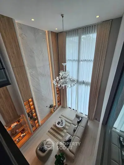 Luxurious high-ceiling living room with elegant chandelier and floor-to-ceiling windows