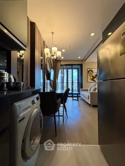 Modern apartment interior with open kitchen and cozy living area, featuring a washing machine and elegant decor.