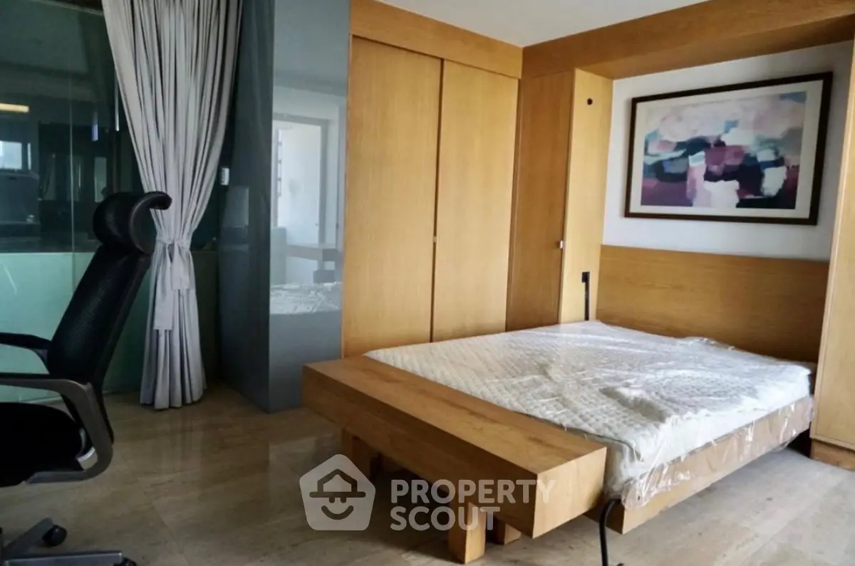 Modern bedroom with wooden furniture and abstract art, featuring a sleek office chair and large window curtains.