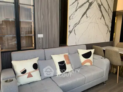 Modern living room with stylish decor and marble accent wall, featuring a cozy gray sofa and chic dining area.