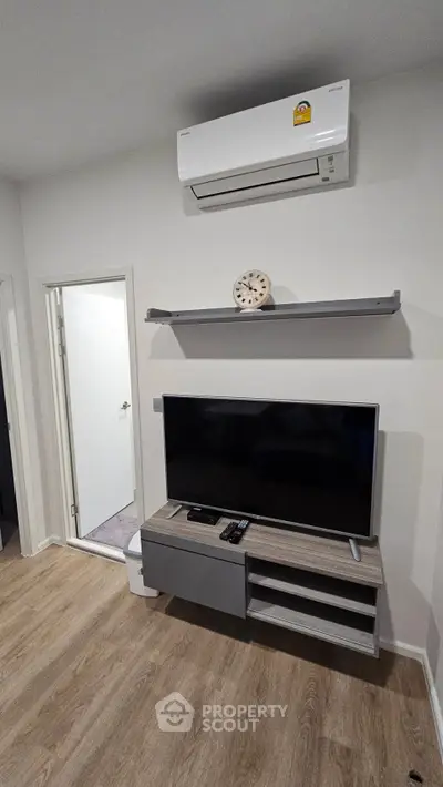Modern living room with sleek TV stand and air conditioning unit, showcasing minimalist design and comfort.