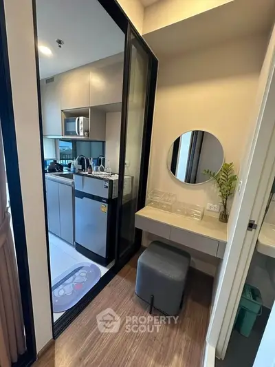 Modern compact kitchen with sleek appliances and cozy seating area in stylish apartment.