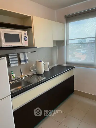 Modern kitchen with microwave, kettle, and large window offering city views.