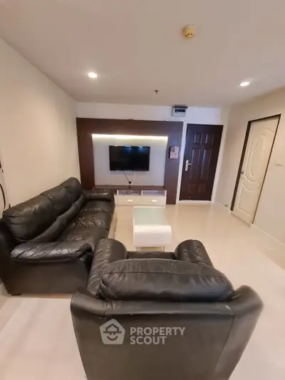 Modern living room with leather sofas and wall-mounted TV in a cozy apartment.