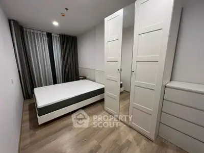 Modern bedroom with sleek white furniture and large mirrored wardrobe in a stylish apartment.