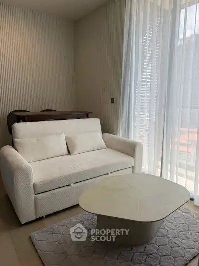 Modern living room with elegant white sofa and stylish coffee table by large window.
