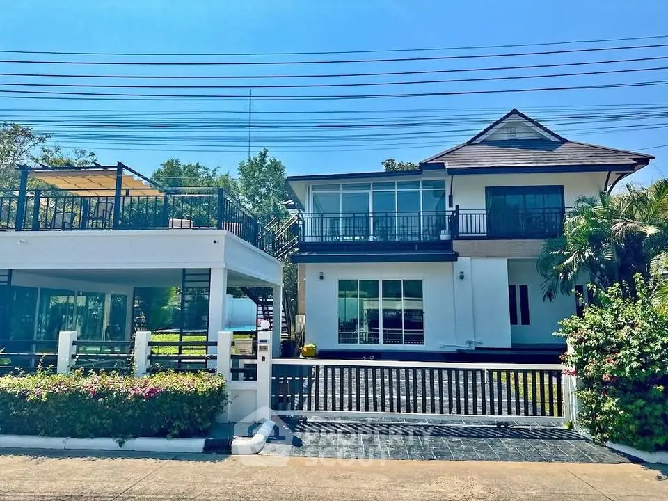 Stunning modern two-story house with spacious balcony and lush greenery.