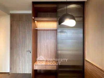Modern wooden wardrobe with sliding glass door and built-in lighting in a stylish interior.