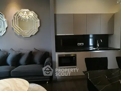 Modern living room with sleek kitchen, elegant mirrors, and plush sofa in stylish apartment.