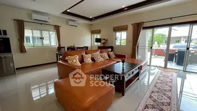 Spacious living room with modern leather sofa and large windows offering natural light.