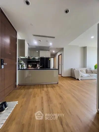 Modern open-layout kitchen and living room with wooden flooring and sleek design.