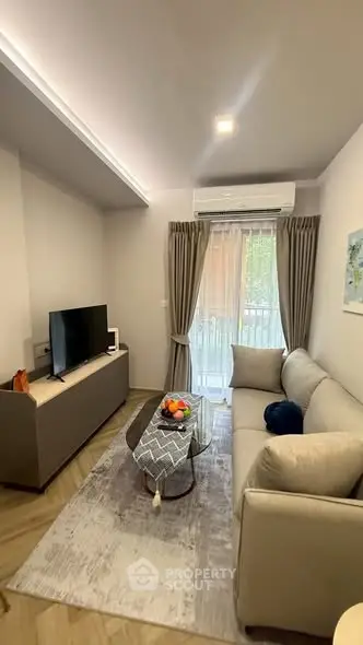 Modern living room with cozy sofa and TV, featuring elegant decor and natural light.