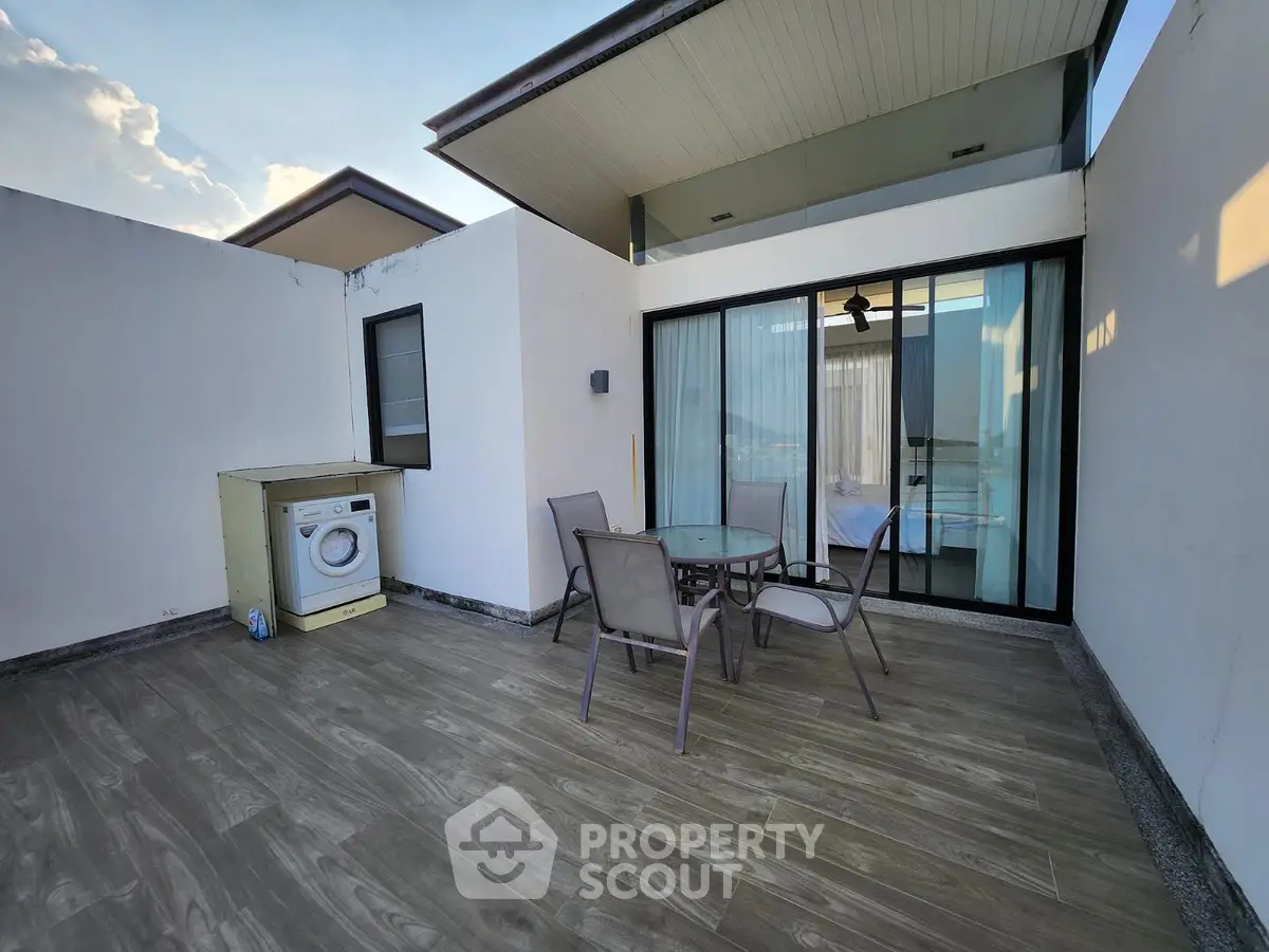 Spacious rooftop terrace with modern furniture and washing machine, ideal for relaxation.