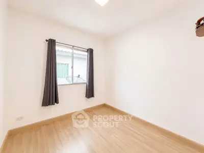 Spacious empty room with wooden flooring and window, perfect for customization.