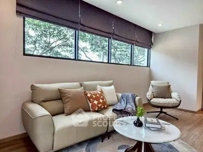 Stylish living room with modern furniture and large windows offering natural light and greenery views.