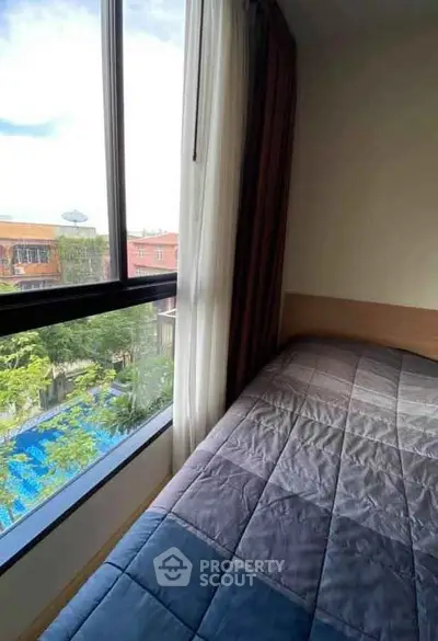 Cozy bedroom with large window offering a scenic view of the neighborhood and pool.