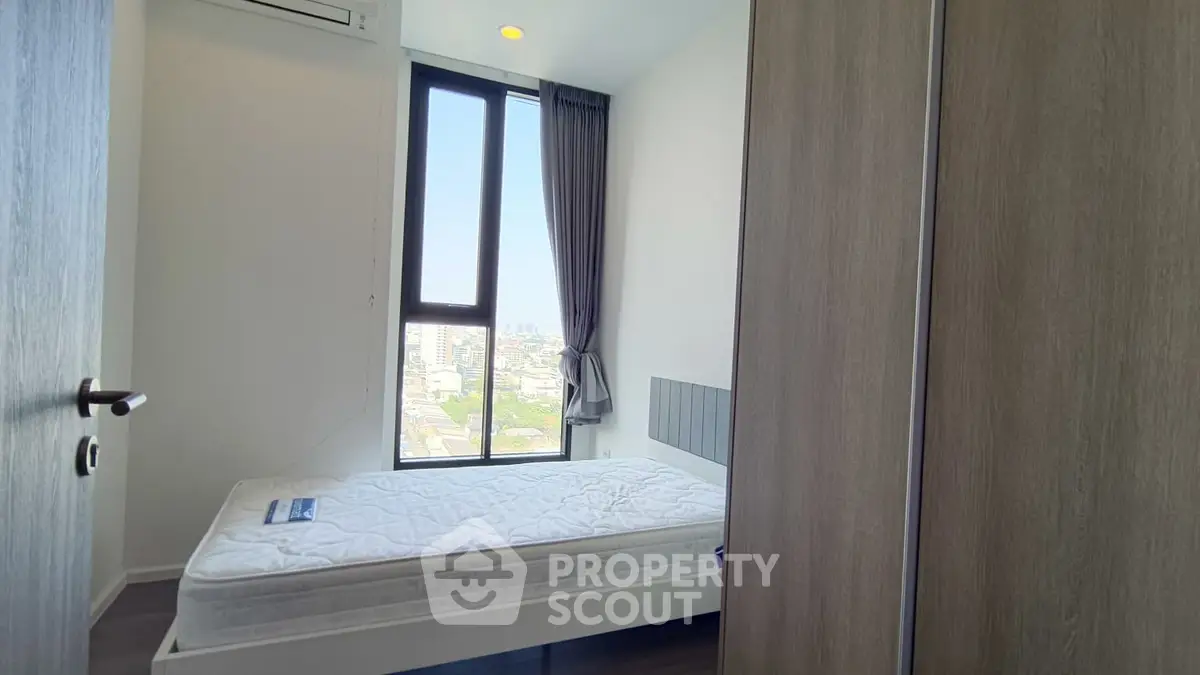 Modern bedroom with large window offering city view and minimalist decor.