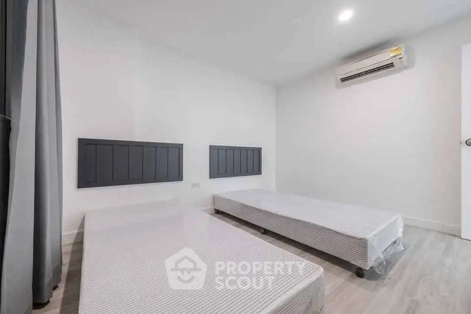 Spacious bedroom with twin beds and modern air conditioning unit.