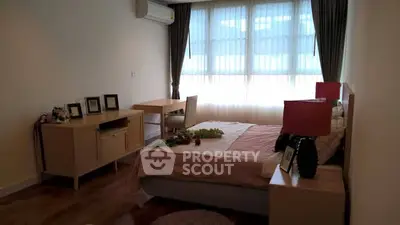 Cozy bedroom with natural light, featuring a desk and stylish decor.