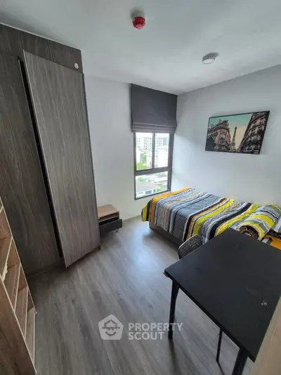 Modern bedroom with stylish decor and city view, featuring a cozy bed and sleek furniture.