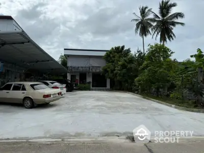 Spacious parking area in front of a modern building with lush greenery and palm trees.