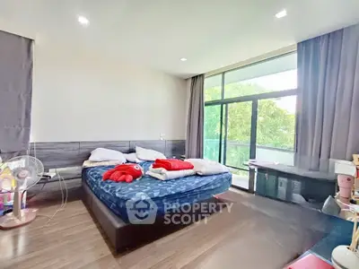 Spacious bedroom with large windows and modern decor, perfect for comfortable living.