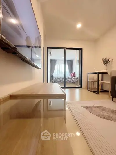Modern living room with sleek TV setup and view into cozy bedroom