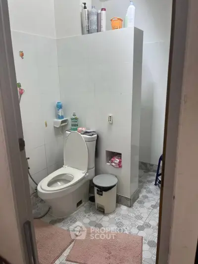 Cozy bathroom with modern fixtures and tiled flooring, featuring a toilet and essential amenities.