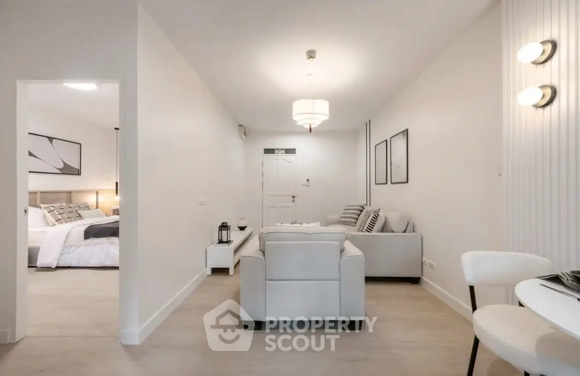 Modern living room with neutral decor and view into cozy bedroom
