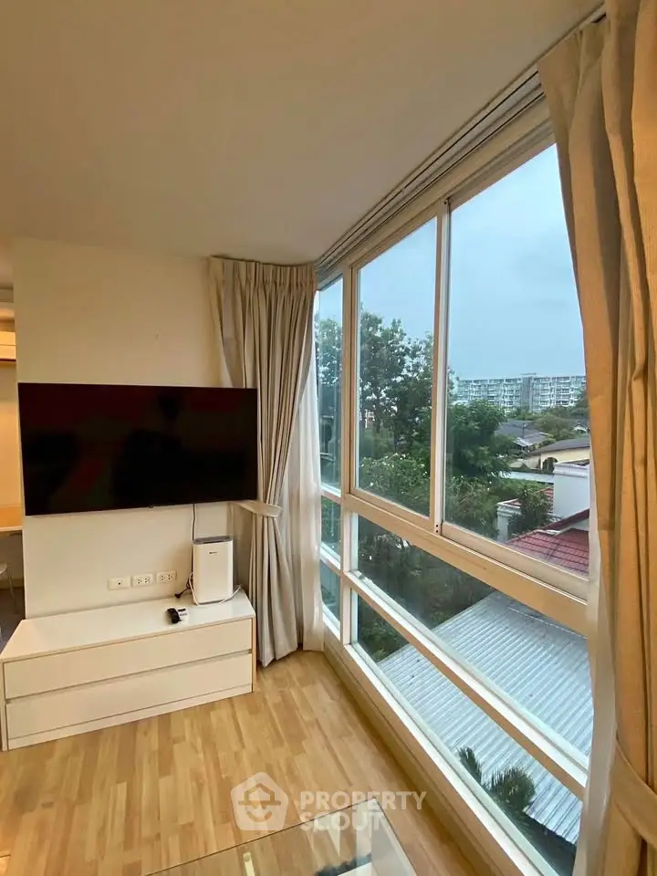 Bright living room with large windows offering a scenic view, featuring modern decor and wooden flooring.