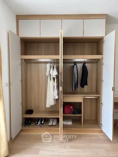 Spacious wooden wardrobe with organized clothing and accessories in modern bedroom.