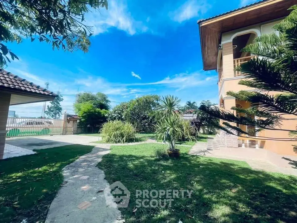 Charming two-story home with lush garden and vibrant blue sky, perfect for serene living.