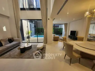 Luxurious open-plan living room with pool view, elegant decor, and high ceilings.