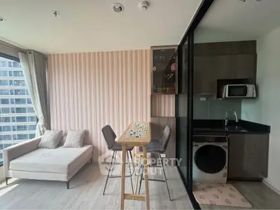 Modern studio apartment with stylish kitchen and cozy living area, featuring a washing machine and microwave.