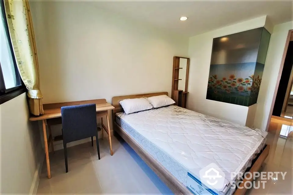 Cozy bedroom with natural light, featuring a comfortable bed and study desk.