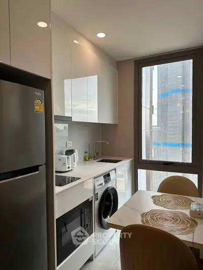 Modern kitchen with sleek appliances and large window view in urban apartment