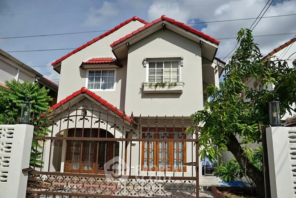 Charming two-story house with red roof and lush garden, perfect for family living.