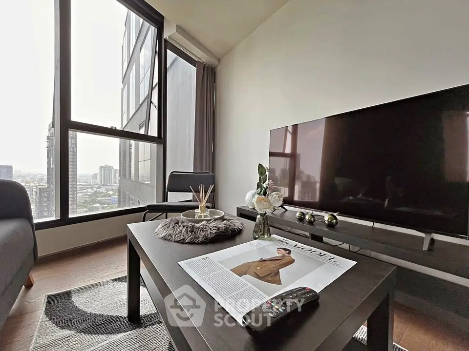 Modern living room with large windows and city view, featuring sleek furniture and decor.