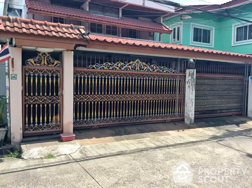 Charming residential property with ornate gate and tiled roof in a suburban neighborhood.