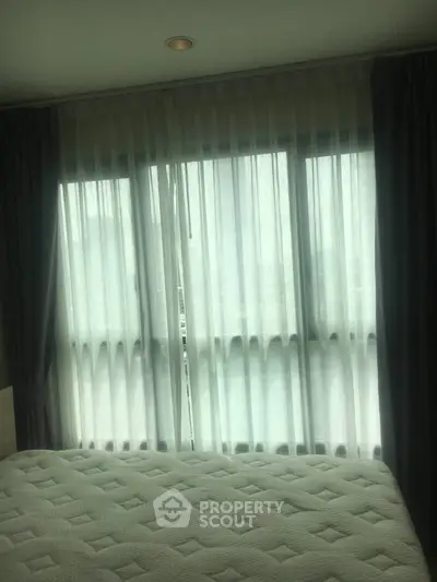 Cozy bedroom with large window and elegant curtains, perfect for natural light lovers.
