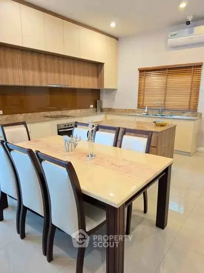 Modern kitchen with dining area, featuring sleek cabinetry and elegant dining table.